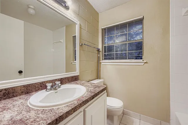 a bathroom with a granite countertop sink a toilet and a mirror