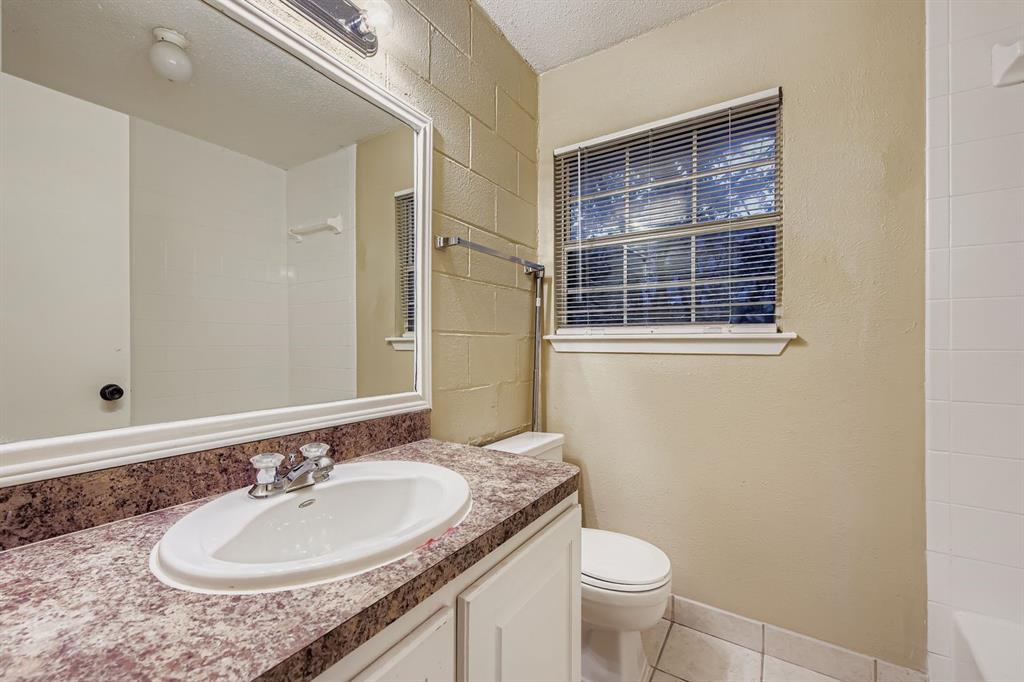 214 Austin Street Grapevine, TX 76051 - Photo 16 of 28 a bathroom with a granite countertop sink a toilet and a mirror