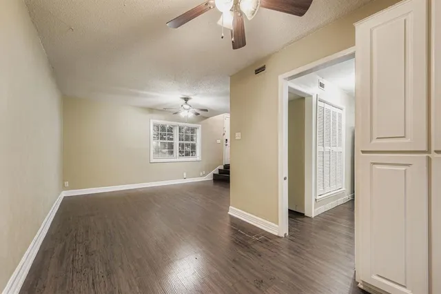 an empty room with wooden floor cabinet and windows