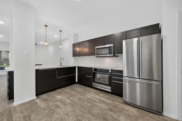 a kitchen with stainless steel appliances kitchen island granite countertop a sink and a stove top oven