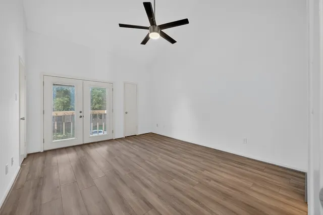 an empty room with wooden floor and a ceiling fan