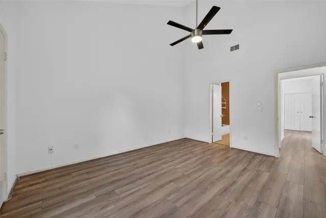 a view of empty room with wooden floor and ceiling fan