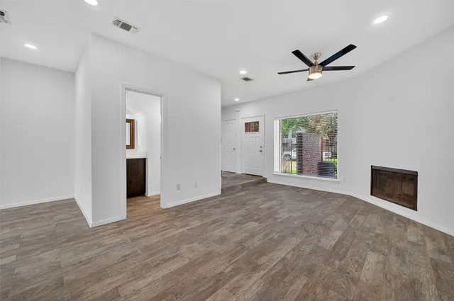 a view of an empty room with a window and a kitchen