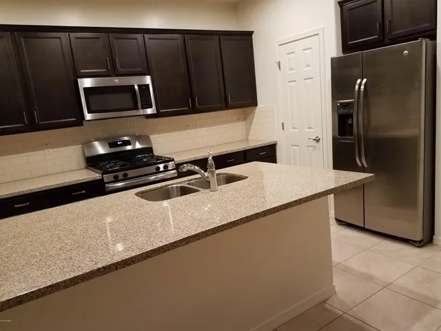a kitchen with granite countertop a refrigerator a stove and a sink