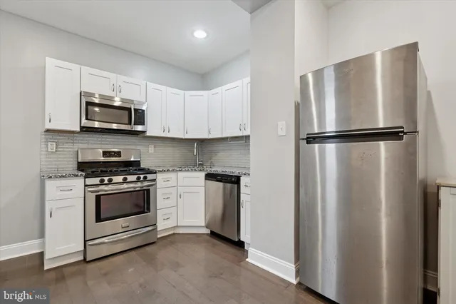 a kitchen with stainless steel appliances white cabinets and a refrigerator