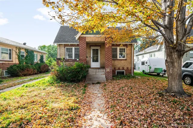 a view of a house with a small yard and large tree