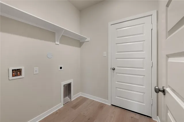 an empty room with wooden floor chandelier and windows