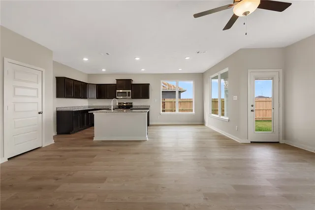 a kitchen with stainless steel appliances granite countertop a stove top oven a sink and a refrigerator with wooden floor