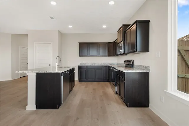 an empty room with wooden floor chandelier fan and windows