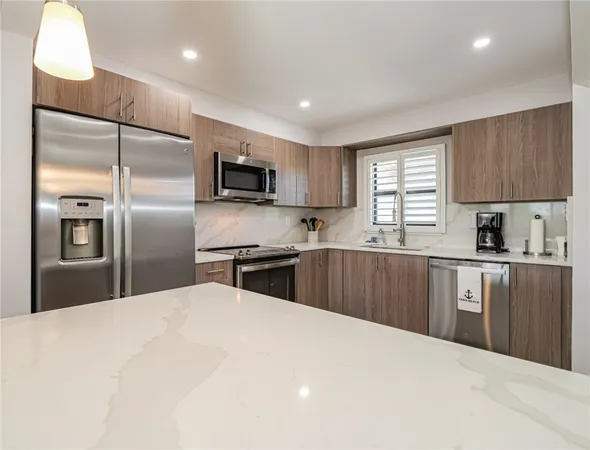 a kitchen with granite countertop a refrigerator a sink a stove a microwave a counter top cabinets and a window
