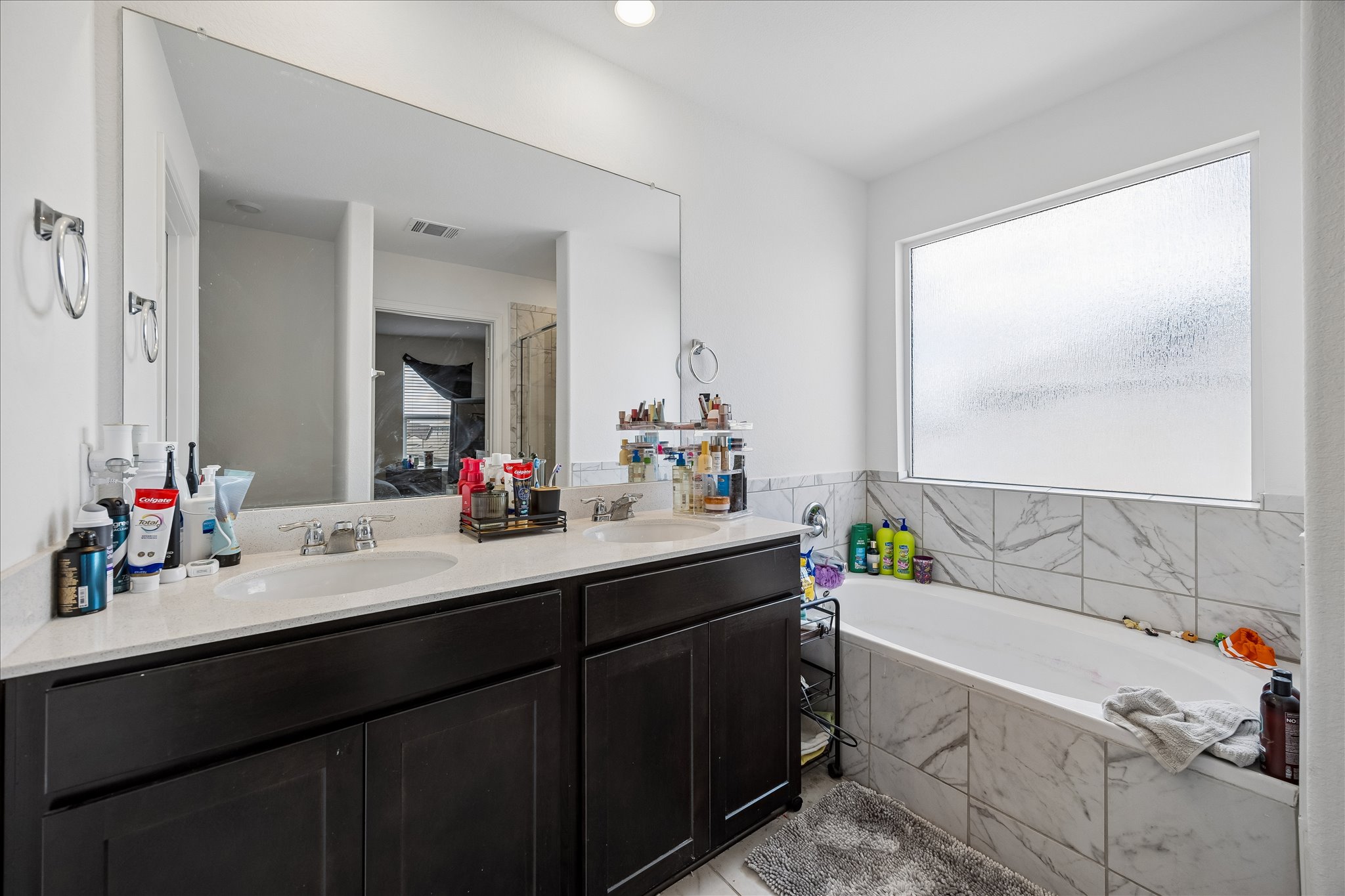 217 Canley Loop Hutto, TX 78634 - Photo 21 of 36 A well-appointed primary bathroom features dual vanities and a relaxing soaking tub.
