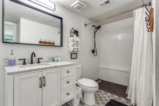 a bathroom with a granite countertop sink toilet a mirror a vanity and shower