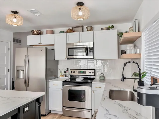 a kitchen with granite countertop a refrigerator stove and sink