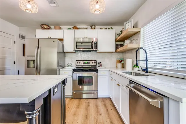 a kitchen with stainless steel appliances a sink stove refrigerator and cabinets