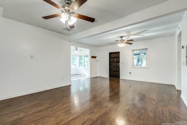 a view of an empty room with window and wooden floor