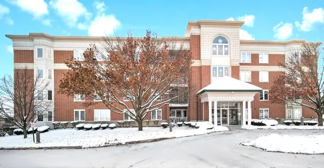 a front view of a building with street and trees