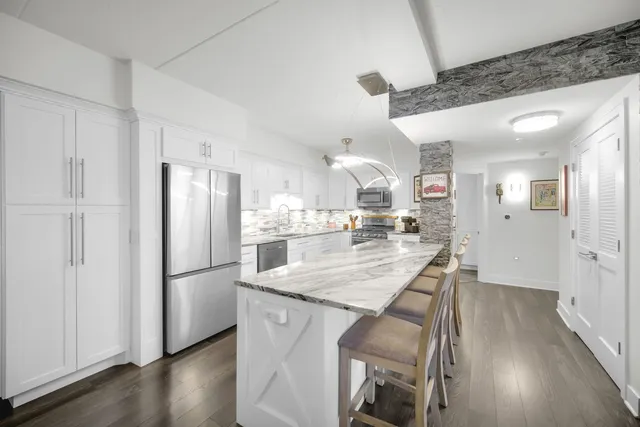 a kitchen with stainless steel appliances granite countertop a refrigerator a sink dishwasher a stove and a refrigerator with wooden floor