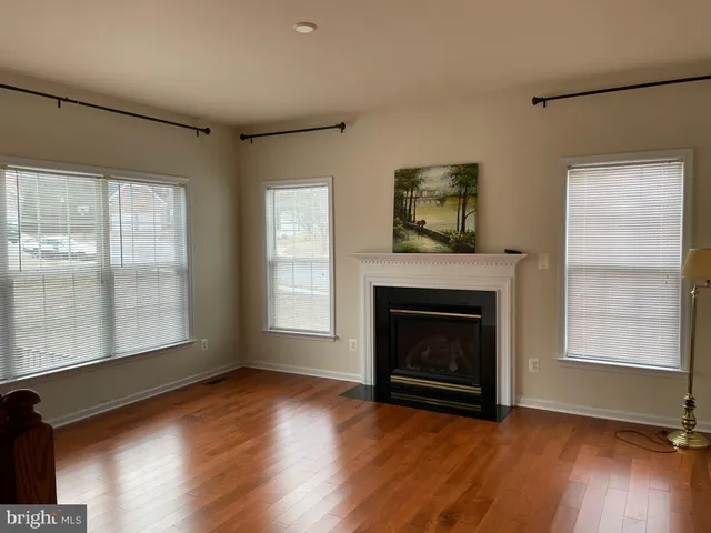 an empty room with wooden floor fireplace and windows