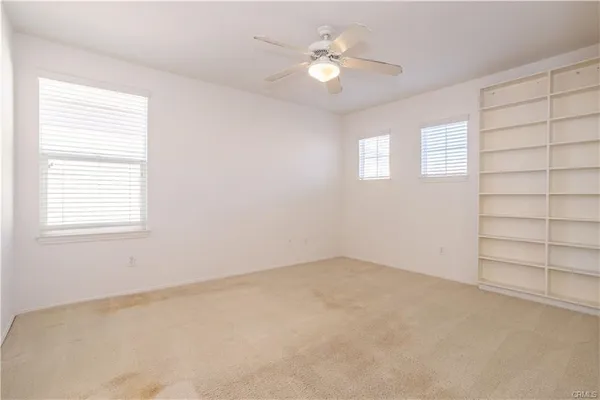 an empty room with a empty space windows and chandelier fan