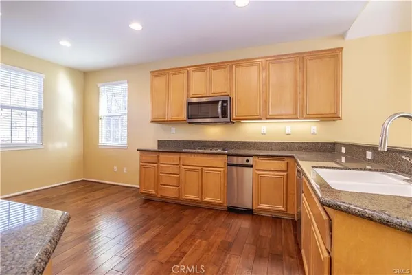 a kitchen with granite countertop wooden floors a sink and a microwave