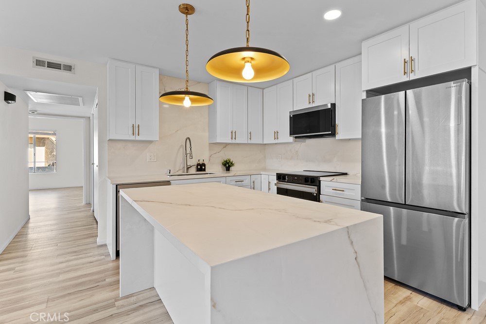 21921 Rimhurst Drive, Unit 128 Lake Forest, CA 92630 - Photo 4 of 24 a kitchen with stainless steel appliances a stove a refrigerator a sink and a microwave