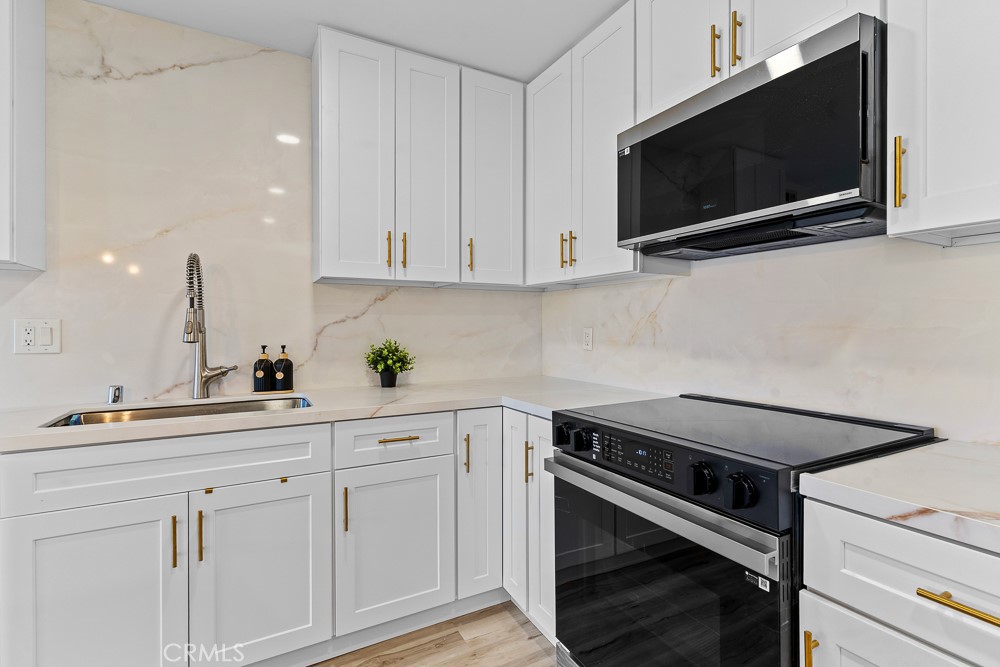 21921 Rimhurst Drive, Unit 128 Lake Forest, CA 92630 - Photo 6 of 24 a kitchen with white cabinets stainless steel appliances and sink