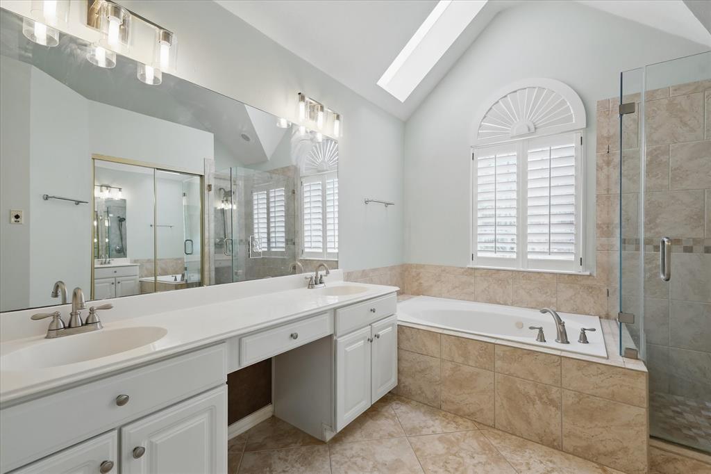 14625 Windsor Court Addison, TX 75001 - Photo 21 of 40 a spacious bathroom with a sink a large mirror and a bathtub next to a window