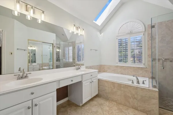 a spacious bathroom with a sink a large mirror and a bathtub next to a window