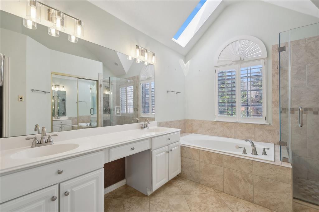 14625 Windsor Court Addison, TX 75001 - Photo 33 of 40 a spacious bathroom with a sink a large mirror and a bathtub next to a window