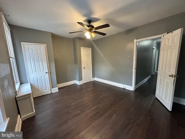 an empty room with wooden floor and a ceiling fan