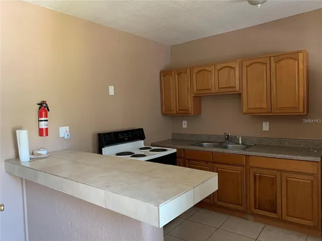 a kitchen with a sink dishwasher and a stove with wooden cabinets