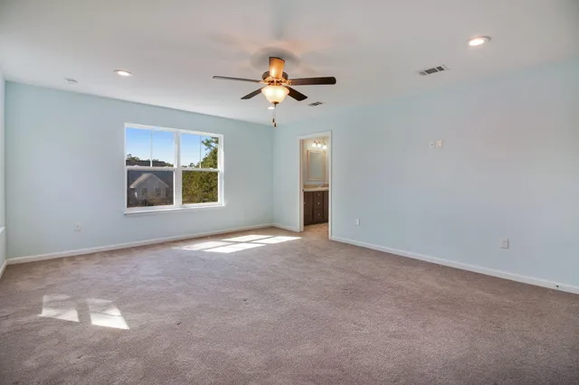 an empty room with windows and ceiling fan