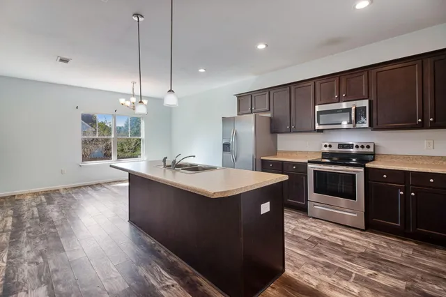 a kitchen with kitchen island granite countertop stainless steel appliances and wooden cabinets