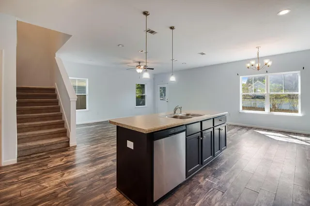 a kitchen with stainless steel appliances granite countertop a sink and a wooden floor