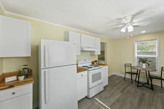 a kitchen with a refrigerator a stove a dining table and chairs with wooden floor