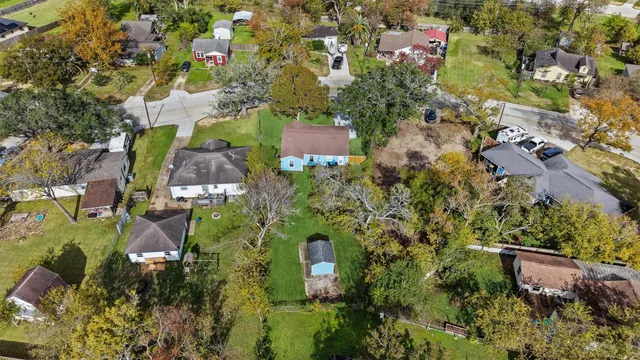 an aerial view of residential houses with outdoor space and trees all around