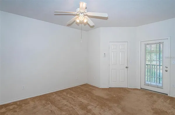 an empty room with a chandelier fan and windows