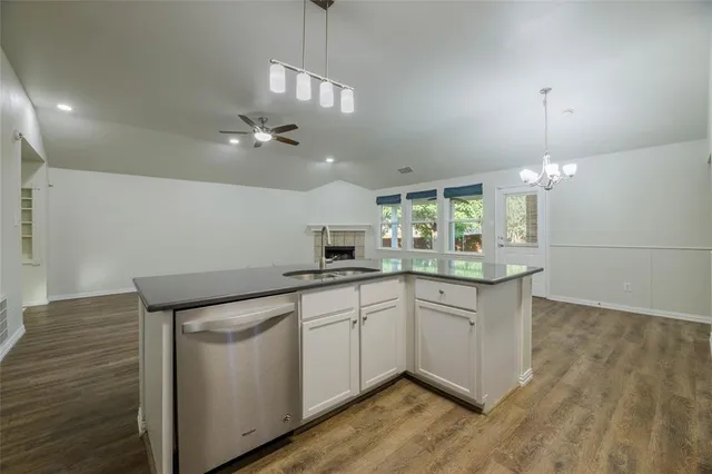 a kitchen with a sink chandelier and wooden floor