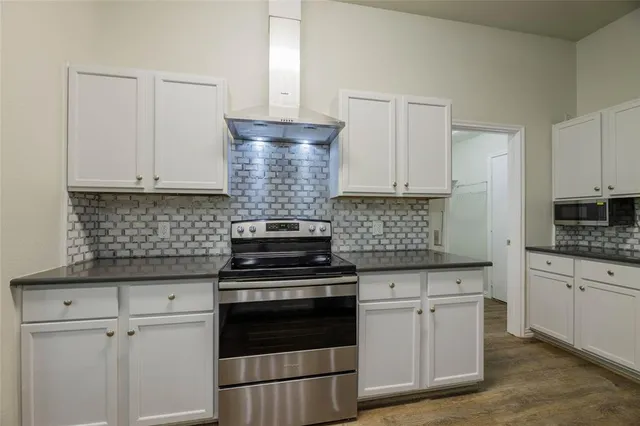 a kitchen with granite countertop white cabinets and stainless steel appliances