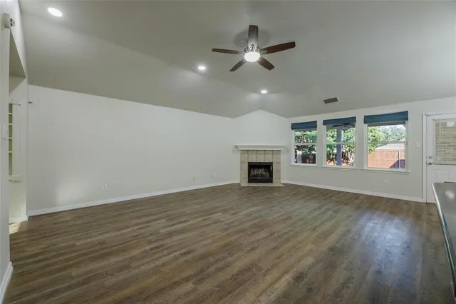 an empty room with wooden floor fireplace and windows