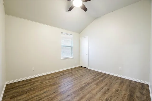 an empty room with ceiling fan and window