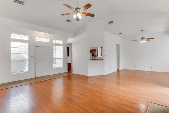 a view of an empty room with window and wooden floor