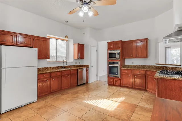 a large kitchen with stainless steel appliances granite countertop a refrigerator and a stove top oven