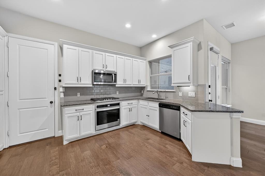 4224 Riverside Drive Flower Mound, TX 75028 - Photo 8 of 23 a kitchen with stainless steel appliances granite countertop white cabinets a sink a stove a refrigerator and microwave with wooden floor