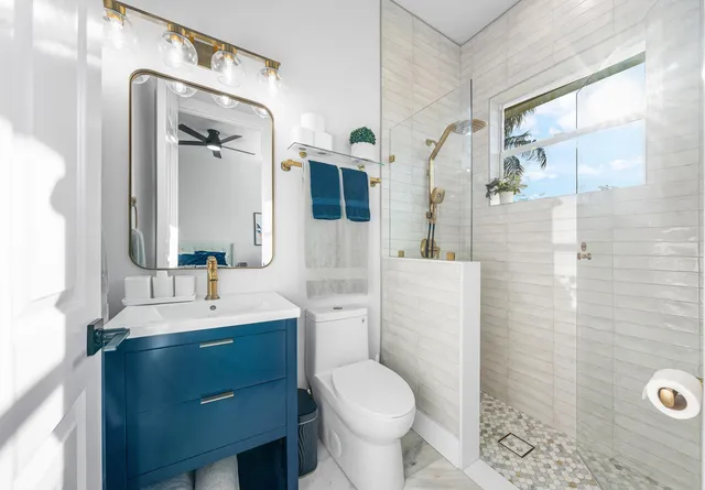 a bathroom with a sink a toilet a mirror and shower