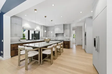 a large kitchen with lots of white furniture a sink a dining table and chairs