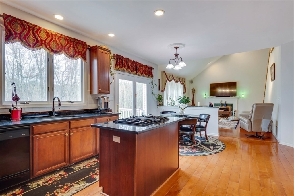22 Robert Road Marlborough, MA 01752 - Photo 10 of 42 a kitchen with stainless steel appliances granite countertop a stove top oven a dining table and chairs with the living room