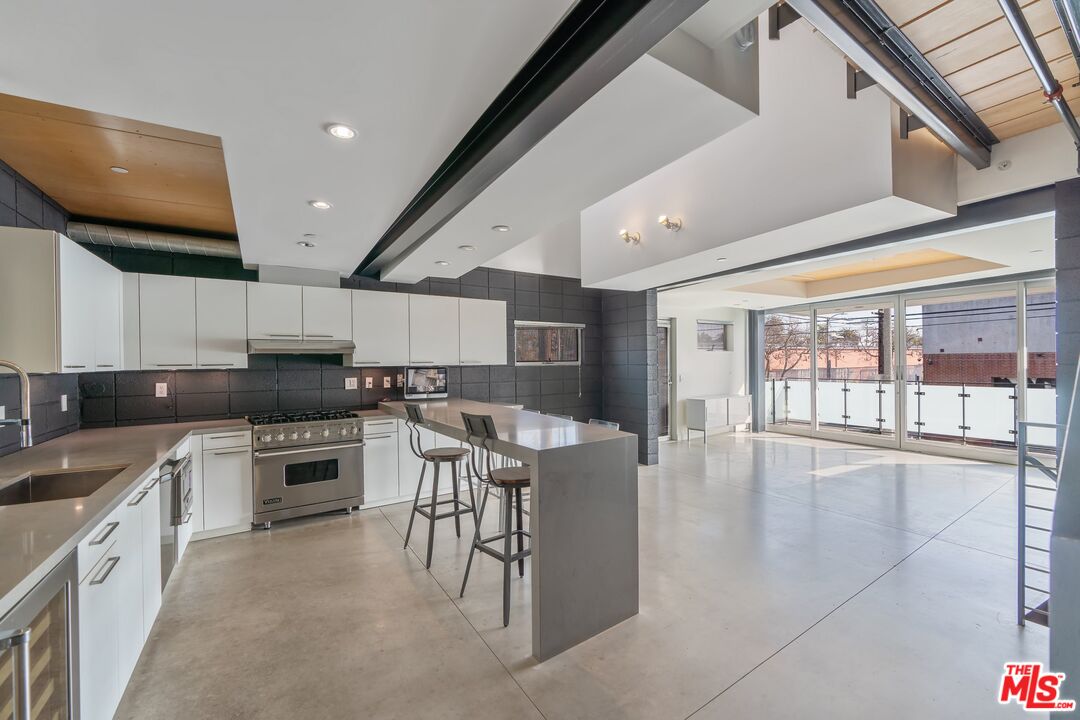 351 Sunset Avenue, Unit 1 Venice, CA 90291 - Photo 8 of 25 a kitchen with stainless steel appliances granite countertop a stove top oven a sink a dining table and chairs with wooden floor