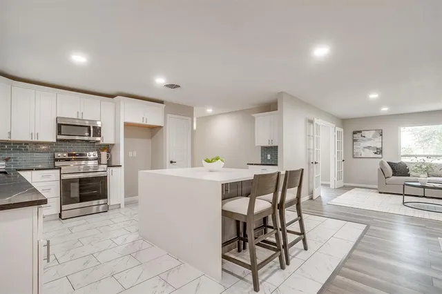 a kitchen with microwave a stove and chairs