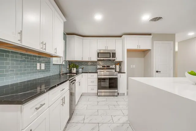 a kitchen with granite countertop a sink a counter top space stainless steel appliances and cabinets